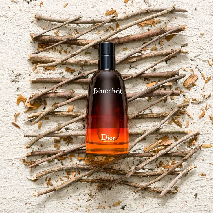 Dior Fahrenheit perfume bottle on a textured surface with twigs